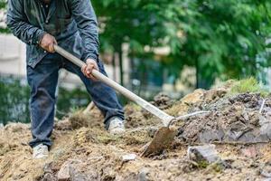 il giardiniere scava il terreno con la sua attrezzatura per il giardinaggio e prepara il terreno per la piantagione. foto