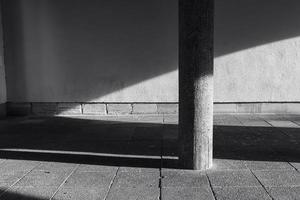 colonna di pietra davanti a un muro con ombra e luce solare foto