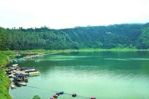 splendida vista sul lago con le barche in alto e la foresta accanto foto