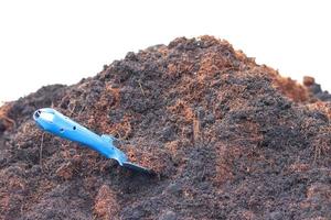 mucchio di terra e polvere di cocco con una pala blu isolata su sfondo bianco. foto