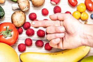 mano che tiene integratori alimentari su frutta e verdura per uno stile di vita sano foto