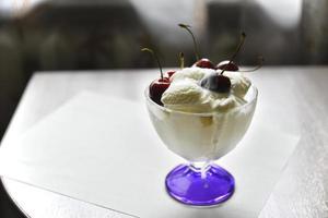 gelato dolce cremoso in una gelatiera di vetro con grandi bacche di ciliegia foto