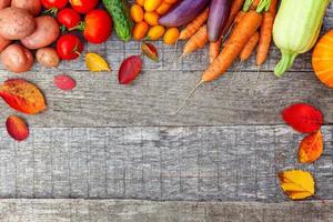 assortimento di diverse verdure biologiche fresche su sfondo di legno in stile country. cibo sano concetto di dieta vegetariana vegana. l'orto locale produce cibo pulito. cornice vista dall'alto spazio di copia piatta. foto