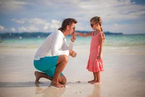 papà che bacia la mano della sua piccola figlia sulla spiaggia esotica foto