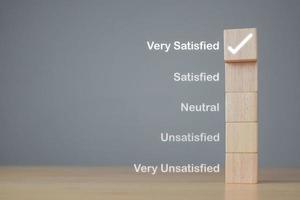 concetto di valutazione e soddisfazione. sui blocchi di legno, un segno corretto indica clienti molto soddisfatti. copia spazio su sfondo grigio. foto