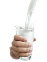mano con un bicchiere di latte su sfondo bianco foto