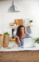 acquisto online sorridente della donna facendo uso del computer e della carta di credito dentro