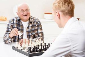 nipote e nonno giocano a scacchi in cucina foto