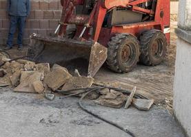 rimozione del lavoratore del team di vecchi pavimenti con mini escavatore