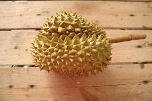 durian, un grande frutto adagiato su un pavimento di assi marroni. è un frutto della Thailandia che abbonda in estate. foto