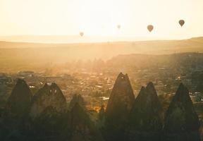 Alba dorata sulla città di goreme in cappaocia lato anteriore direzionale della luce del sole con palloncini in aria nella soleggiata nebbiosa mattina calma autunnale foto