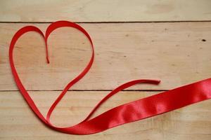 design consapevolezza del nastro a forma di cuore rosso su sfondo di legno invecchiato vecchio. concetto di San Valentino. spazio per il testo. foto
