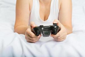 giovane donna caucasica che gioca console per videogiochi sul letto