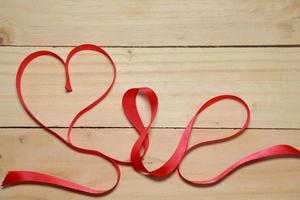 design consapevolezza del nastro a forma di cuore rosso su sfondo di legno invecchiato vecchio. concetto di San Valentino. spazio per il testo. foto