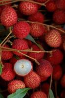 litchi, litchi freschi e pelati che mostrano la buccia rossa e la polpa bianca con foglia verde. foto