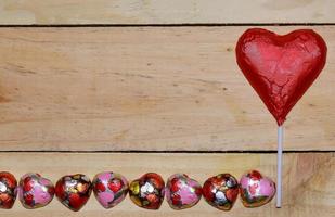 cuore di cioccolato avvolto in rosso su legno. concetto di San Valentino. spazio per il testo. foto