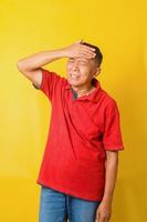 salute, dolore, stress, vecchiaia e concetto di persone - uomo anziano asiatico che soffre di mal di testa isolato su sfondo giallo. foto