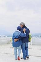 il lato posteriore della coppia matura romantica si abbraccia e vede il paesaggio. marito che sorride e abbraccia la moglie. concetto di coppia di anziani di felicità. foto