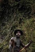 ritratto dell'uomo della tribù dani che indossa koteka, abiti tradizionali della papua. uomini della tribù dani che si guardano intorno e pronti a cacciare prede animali sulla riva del fiume. foto