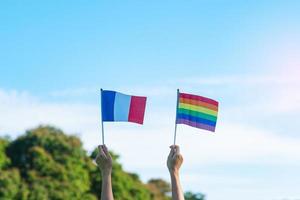 mani che mostrano lgbtq arcobaleno e bandiera francese sullo sfondo della natura. sostenere la comunità lesbica, gay, bisessuale, transgender e queer e il concetto di mese dell'orgoglio foto