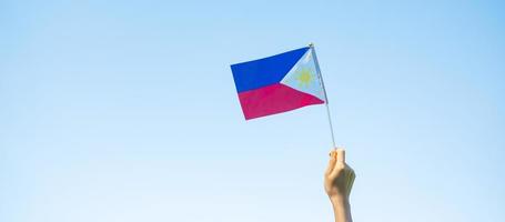 mano che tiene la bandiera delle Filippine sullo sfondo della natura. 12 giugno del giorno dell'indipendenza e dei concetti di celebrazione felice foto