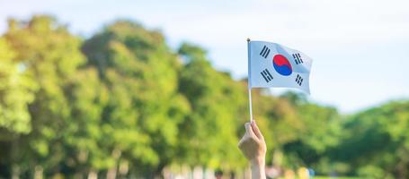 mano che tiene la bandiera della Corea sullo sfondo della natura. fondazione nazionale, gaecheonjeol, festa nazionale della nazione, giorno della liberazione nazionale della Corea e concetti di felice celebrazione foto