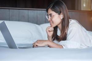 donna felice che usa il laptop per lavoro, riunione femminile online dal computer portatile sul letto. tecnologia, rete, lavoro da casa, stile di vita e concetto di comunicazione digitale foto