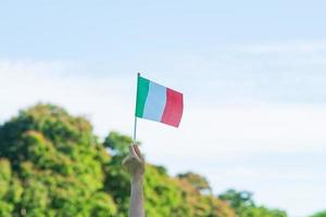 mano che tiene la bandiera dell'italia sullo sfondo della natura. concetti di festa nazionale, festa della repubblica, festa della repubblica e felice celebrazione foto