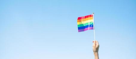 mani che mostrano la bandiera arcobaleno lgbtq sullo sfondo della natura. sostenere la comunità lesbica, gay, bisessuale, transgender e queer e il concetto di mese dell'orgoglio foto