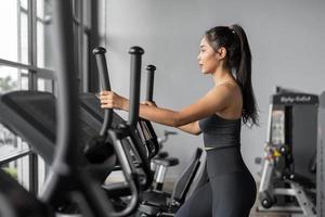esercizi di donna asiatica in fitness. la giovane donna in buona salute in abbigliamento sportivo è esercizi cardio in palestra. foto