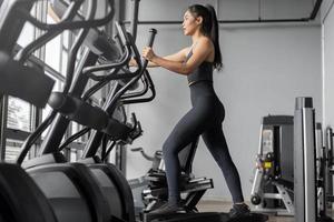 esercizi di donna asiatica in fitness. la giovane donna in buona salute in abbigliamento sportivo è esercizi cardio in palestra. foto