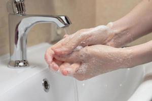 igiene. lavarsi le mani. lavarsi le mani con il sapone. mano di donna con schiuma. proteggiti dalla pandemia del coronavirus covid-19 foto
