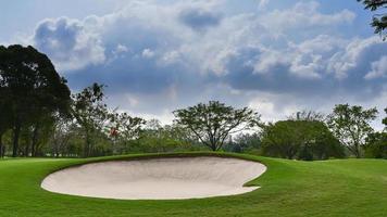 un paesaggio di vista erba verde al campo da golf, grandi alberi con sfondo del cielo di luce solare foto