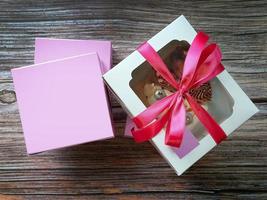 vista dall'alto colore vibrante della torta di freschezza nella scatola di carta bianca e rosa con sfondo in legno foto