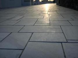 prospettiva della pavimentazione in marmo di forma geometrica con luce solare, passerella nell'isola di oia santorini foto