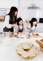 inquadratura di una madre e due figlie che fanno insieme per cuocere in cucina foto