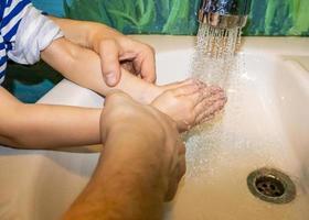 primo piano di uomo caucasico e bambino si lava le mani in bagno. covid - 19 prevenzione foto