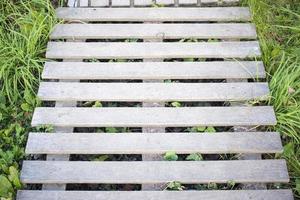 tavole di pallet in legno con erba e fiori selvatici, copia spazio sullo sfondo foto