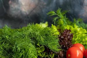 verdure fresche per insalata. pomodori e lattuga, cetrioli con zucchine e cavoli con aneto. raccolto primaverile, benefici e vitamine. su sfondo scuro. foto