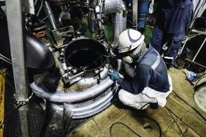 lavoratore maschio test serbatoio in acciaio saldatura di testa guscio in carbonio piastra del serbatoio di stoccaggio olio motore sfondo bianco contrasto del campo magnetico foto