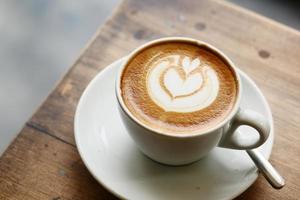 una tazza di caffè in ritardo con un design a forma di fiore in cima al bar foto