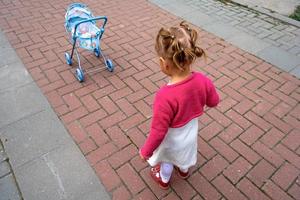 bambina e passeggino per bambola foto