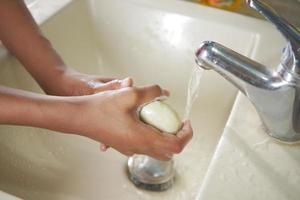 giovane che si lava le mani con acqua calda e sapone foto