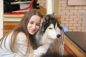 proprietario dell'animale domestico della ragazza che abbraccia con il cucciolo di cane. felice femmina umana e simpatico cane divertente sdraiato sul pavimento insieme foto