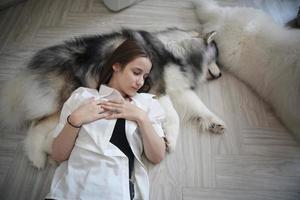 proprietario dell'animale domestico della ragazza che abbraccia con il cucciolo di cane. felice femmina umana e simpatico cane divertente sdraiato sul pavimento insieme foto