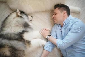 uomo e con il suo cane che gioca sul pavimento. cane felice, ragazzo felice con il cane. foto