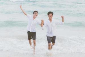 ritratto omosessuale giovane coppia asiatica che corre con allegro insieme sulla spiaggia in estate, asia gay turismo per il tempo libero e relax con felicità in vacanza al mare, concetto legale lgbt. foto