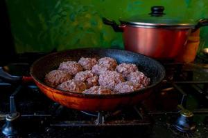 mani dell'uomo che preparano le polpette con carne macinata cruda. stile di vita primo piano composizione con cucina colorata con pareti dipinte. cucina casalinga durante il blocco, concetto di condivisione delle pulizie domestiche. foto