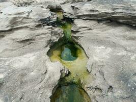 buco nella roccia grigia in spiaggia e acqua a porto rico foto