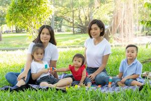 bella giovane famiglia di genitori asiatici picnic ritratto nel parco, bambino o bambini e madre amano felici e allegri insieme in estate al giardino, concetto di stile di vita. foto